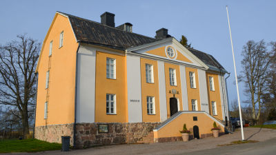 Lovisa stads museum utifrån. En gul stenbyggnad i gammal stil som står ensam på en gräsplätt. 