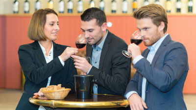 Två män och en kvinna doftar på viner