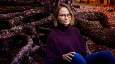 Författaren Maria Grundvall sitter i skogen.