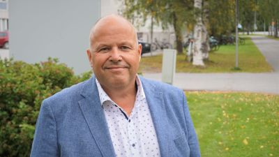 Man i blå kavaj står på en skolgård.