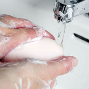 Händer som tvättas med tvål, under en vattenkran.