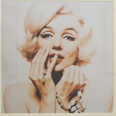 Marilyn Monroe nojaa muotokuvassa poskeensa, toisen käden pikkusormi huulillaan.
