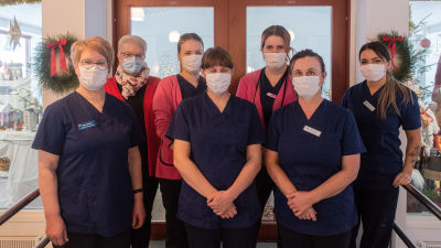 En grupp kvinnliga äldrevårdare i arbetskläder och munskydd.