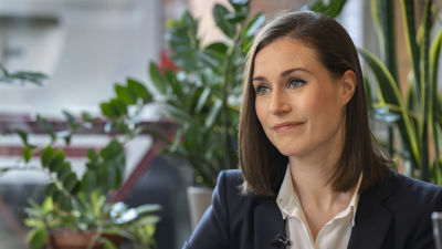 Sanna Marin iklädd kostym och med axellångt här. Hon tittar åt sidan.