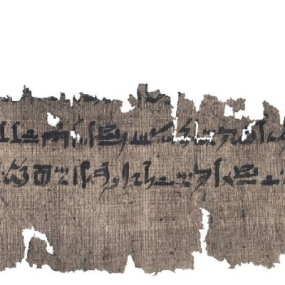 Repalainen palanen papyrusta, jossa näkyy kaksi riviä hieroglyfejä.