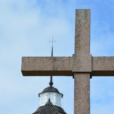 Kirkon torni ja etualalla jyhkeä risti.
