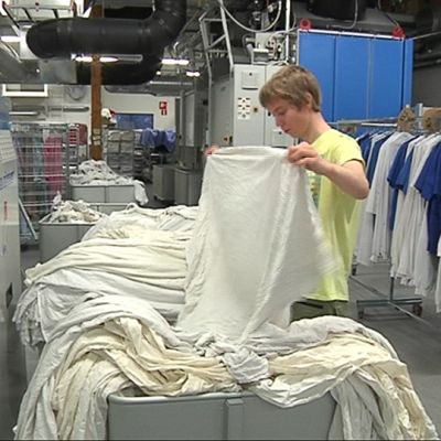 Mies käsittelee lakanoita pesulassa