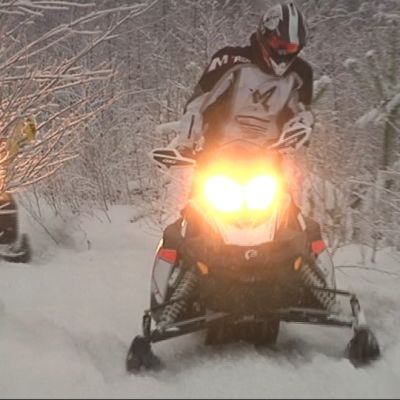 Moottorikelkkoja lumisessa säässä.