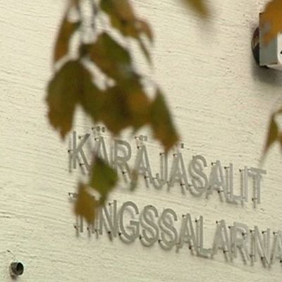 Kuvassa puunlehtien takaa näkyy Kokkolan virastotalon seinä jossa lukee käräjäsalit