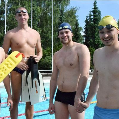 Neljä hengenpelastuskilpailujen mieskilpailijaa altaan reunalla