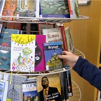 Henkilö ottaa kirjaa kirjaston hyllystä.