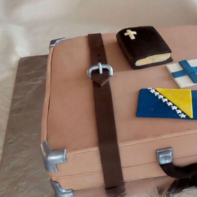 Kuvassa ruskea vanhanaikainen matkalaukku, Jossa Suomen ja Bosnian liput ja raamattu.