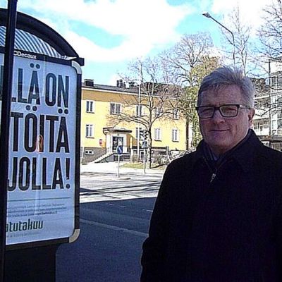 Mies seisoo bussipysäkin vieressä.