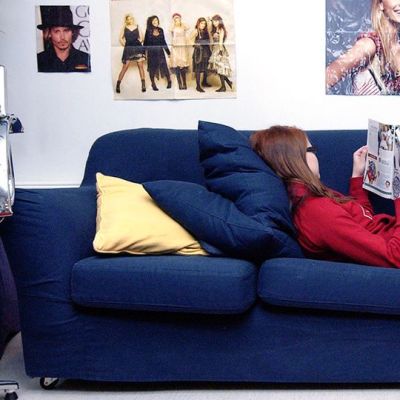 Nuori nainen lukee lehteä sohvalla.
