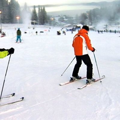Messilässä lasketellaan. Taustalla nousee ilmaan lumipöllyä, kun lumitykit tykittävät uutta lunta.