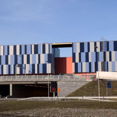 Kauppakeskus Goodmanin eteläfasadi on siniharmaata palapeliä ja marjapuuronväristä seinää.