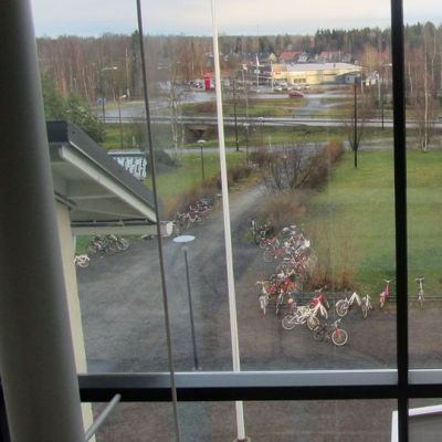 Kuvassa ikkunasta näkyy pihalle, jossa on polkupyöriä ja ruohikkoa