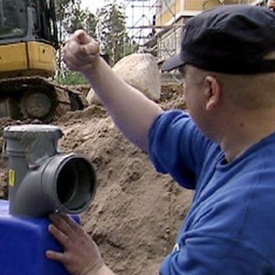 Jätevesien puhdisjärjestelmän asentaminen käynnissaä. Kaivinkone ja apumies.