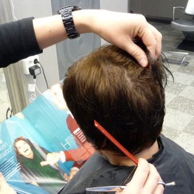 Kampaaja leikkaa asiakkaan hiuksia