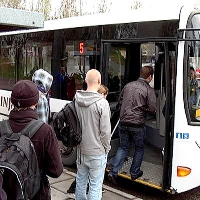Matkustajat nousevat linja-autoon skinnarilassa.