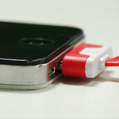 Lähikuva laturinjohdosta ja Iphone-puhelimesta.