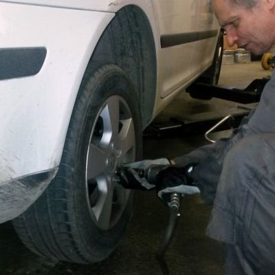 Mies vaihtaa auton takarengasta.