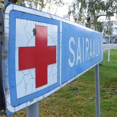 Kyltti, jossa punainen risti ja teksti sairaala.
