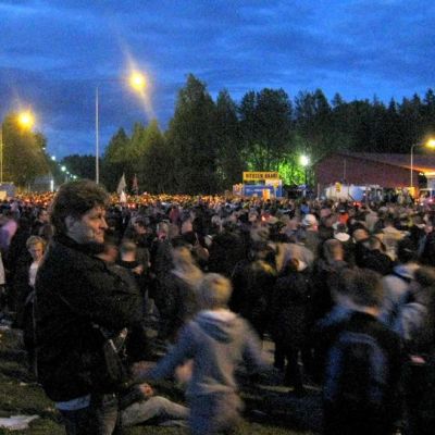 Mies tarkkailee poistuvaa yleisömassaa aidan vieressä