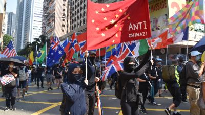 Bild på demonstranter som håller upp en banderoll med Kinas flagga där det står ''Anti-Kina''.