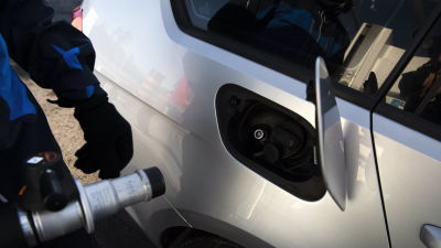 En person håller på att tanka en gasbil.