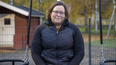 En kvinna sitter i en gunga ute på gården vid ett daghem. Det är daghemmet Karusellen i Karis.