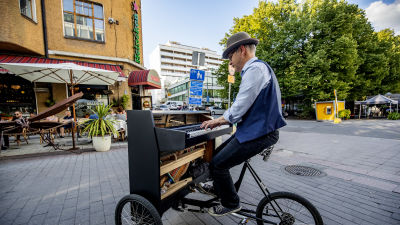En man med hatt spelar på ett portabelt piano.