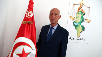 Bild på man som står vid tunisiens flagga.