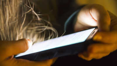 En anonym person ser på sin telefon.