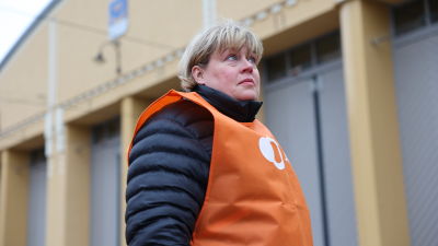 Porträtt på en kvinna som står framför ett gult hus.