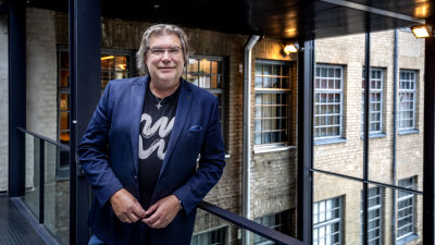 Man, Mikael Lindfelt vid Åbo Akademi, står framför kameran i mörkblå satinkostym.