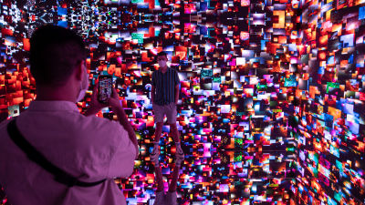 Människor fotograferar det digitala konstverket Machine Hallucination Space: Metaverse Lot 1, av Refik Anadol.