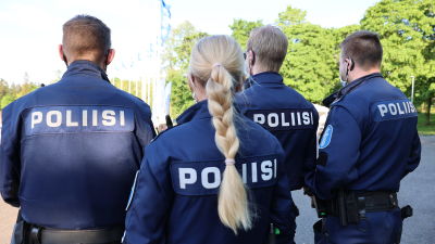 Fyra poliser står på rad med ryggen mot kameran. På uniformen står det "polis" på ryggen.