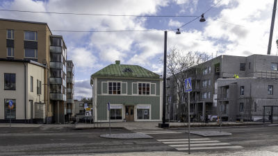 Vanha, vihreä puutalo uudisrakennusten välissä Sipoon Nikkilässä.