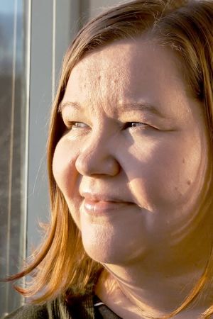 Mari Pulkkinen katsoo ikkunasta talviseen puistomaisemaan.