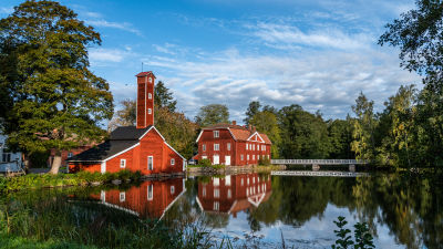 Två gamla röda hus vid en spegelblank sjö på en klar dag