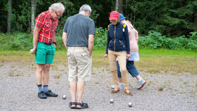 Ett gäng petanque spelare kollar vem som vann omgången