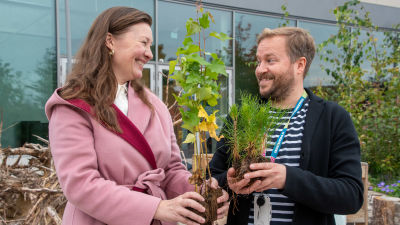 Nina Backman håller i en björkplanta. Bredvid står Thomas Weissman som håller i en tallplanta.
