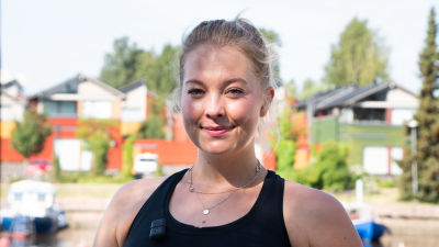 Sara Smeds utomhus. Bakom syns hus på rad.
