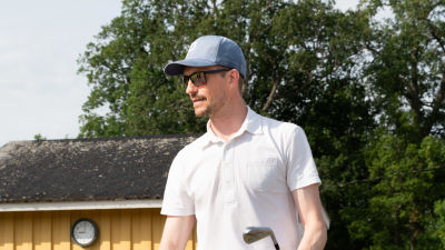 Jonathan Andersson utomhus vid golfplan med golfklubba i handen.