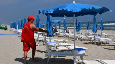 Lorenzo Paupini säsongsarbetar som badvakt på stranden på förmiddagarna och driver en bar på kvällarna. Nu går han på stranden och fäller upp parasollen och ser till solstolarna.