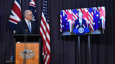 Australiens premiärminister Scott Morrison står och lyssnar på USA:s president Joe Biden som han talar med via videolänk.