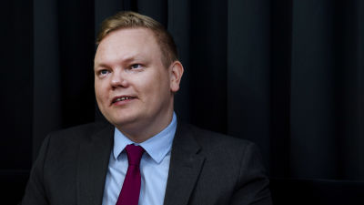 En blond man i svart kostym.