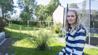Lotta Eskelinen står på sin bakgård. I bakgrunden ser man taket av ett radhus.