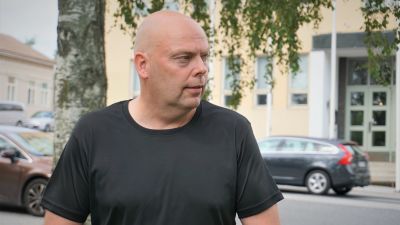 Man i svart t-skjorta står vid en väg.